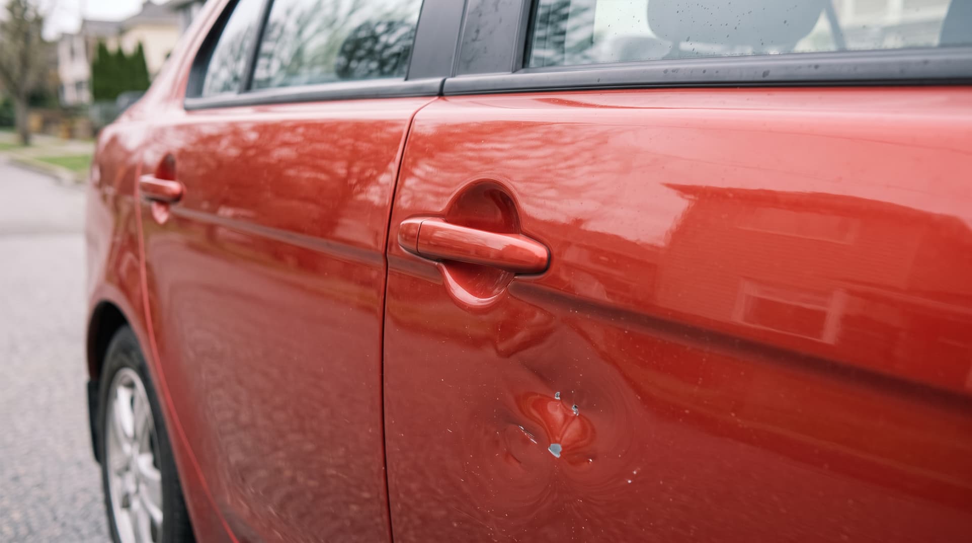 Abolladura en la puerta de un coche rojo para reparar en el taller de chapa y pintura en Valga